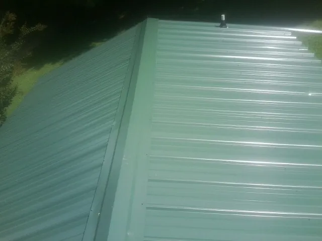 New green metal panels meeting at the ridge of a roof — Flat Roof Repair work by our crew in Nanjemoy