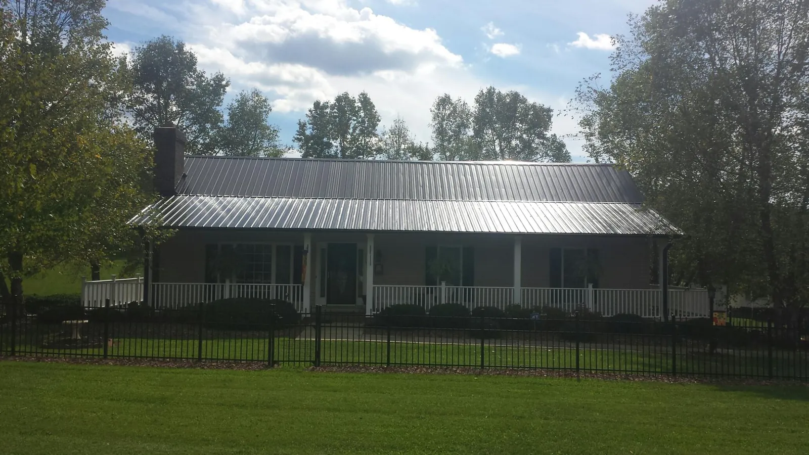 Gray metal roof on a brick ranch with a full width front porch — Gutter Guard Installation work by our crew in Nanjemoy