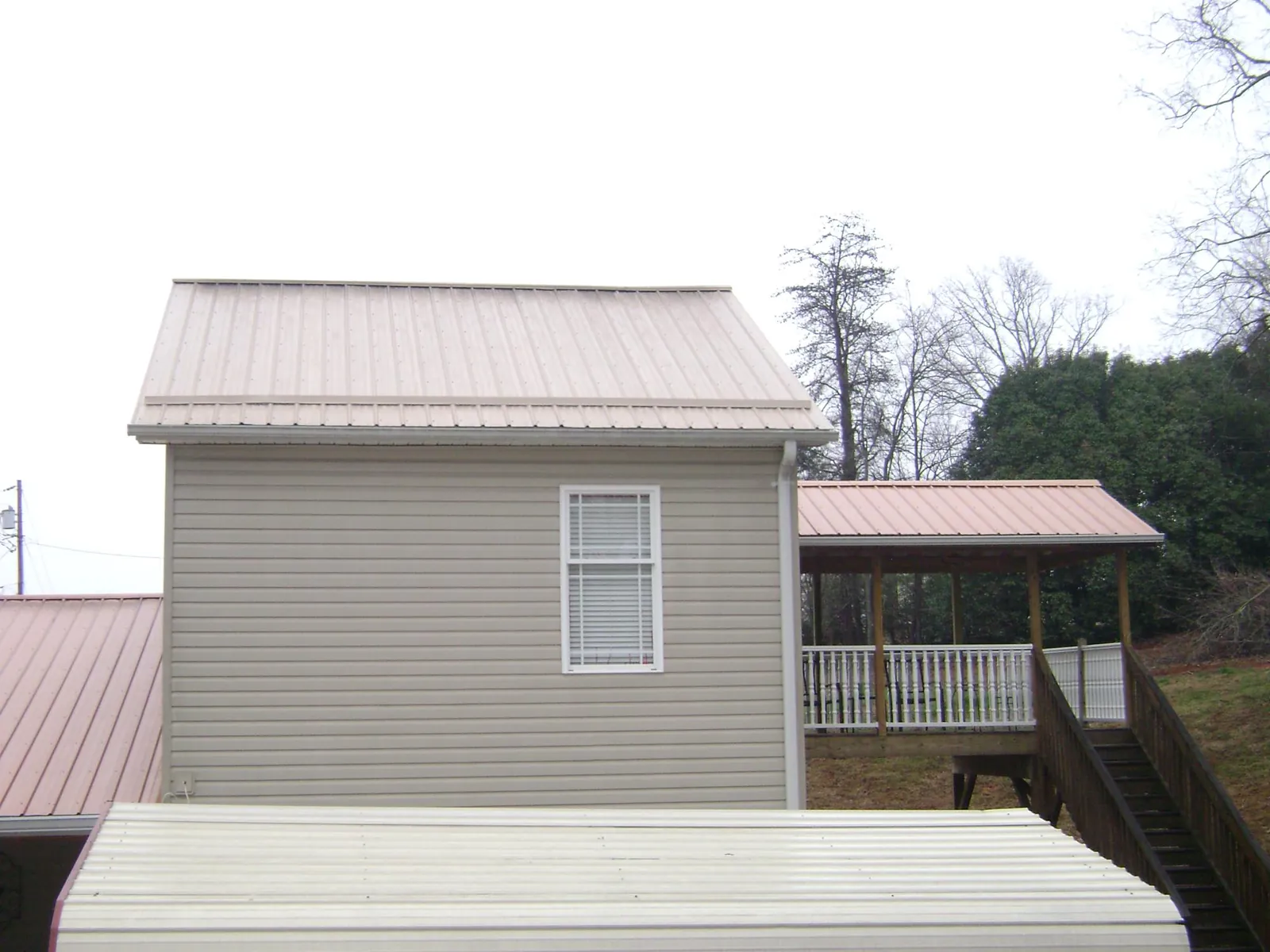 Tan metal roofs on a two story addition and attached porch, from a Roof Replacement job in Nanjemoy